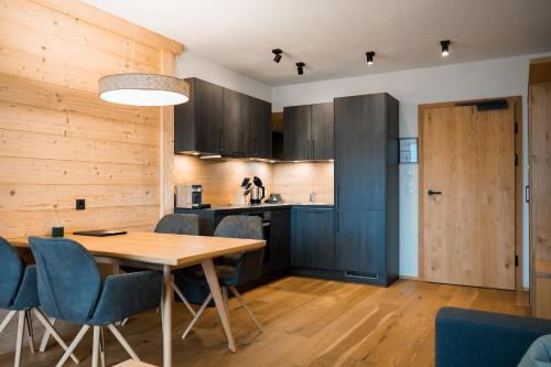 a kitchen and dining room with a wooden table and chairs at Puitalm Apartments & SPA by Peak Stay in Arzl im Pitztal