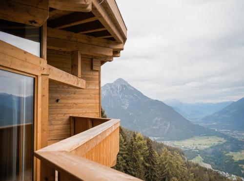 a balcony of a wooden house with a view of mountains at Puitalm Apartments & SPA by Peak Stay in Arzl im Pitztal