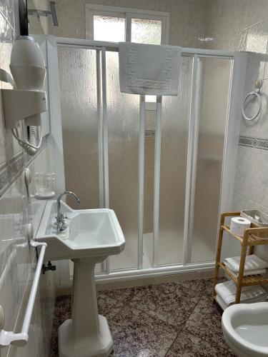 a white bathroom with a shower and a sink at La Despensa del Valle in Restábal