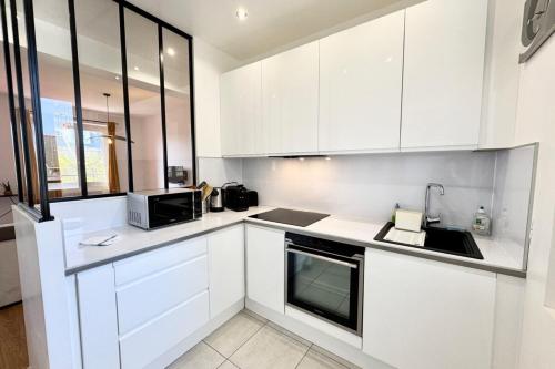 une cuisine blanche avec des armoires blanches et un micro-ondes dans l'établissement T3 lumineux en plein coeur de Lorient -Tout à pied, à Lorient