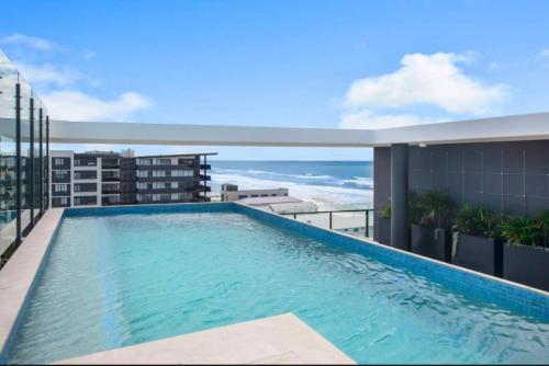 a swimming pool on the roof of a building with the ocean at Luxury Palm Beach Getaway in Gold Coast
