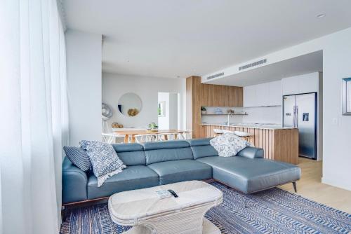 a living room with a blue couch and a kitchen at Luxury Palm Beach Getaway in Gold Coast