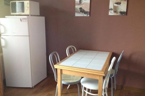 Il comprend une cuisine équipée d'une table avec des chaises et d'un réfrigérateur blanc. dans l'établissement Cozy apartment with balcony and nice mountain view, à Annecy