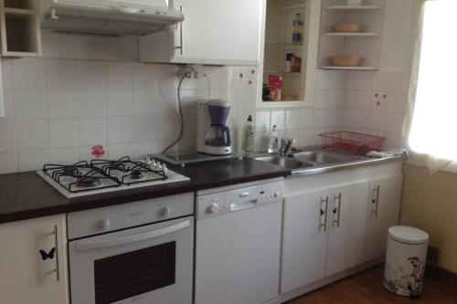 une cuisine blanche avec une cuisinière et un évier dans l'établissement Cozy apartment with balcony and nice mountain view, à Annecy