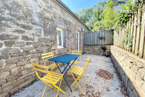 a table and chairs in front of a brick building at Longère de charme cosy - Proche des plages in Ploemeur