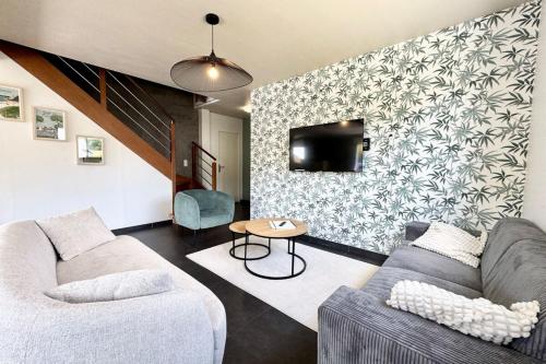 un salon avec un canapé et une télévision sur un mur dans l'établissement Belle maison contemporaine aux portes de Lorient, à Kervignac
