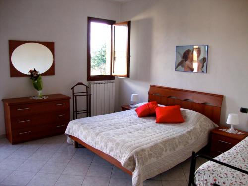 a bedroom with a bed with red pillows and a mirror at Casa Vacanze Alle Porte del Chianti in San Giovanni Valdarno