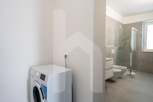 ジュリアノーヴァにあるHomiday - Residenza Oltremareの白いバスルーム(洗濯機付)が備わります。