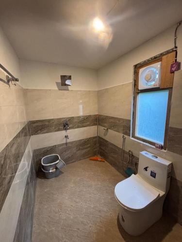 a bathroom with a toilet and a window at Kath Kuni Cafe & Stay Shangarh in Shangarh