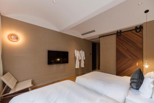 a bedroom with two beds and a tv on the wall at Shanyu Life Huangshan Design Hotel in Huangshan
