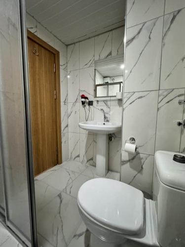a white bathroom with a toilet and a sink at MiTOS APART OTEL in Alanya