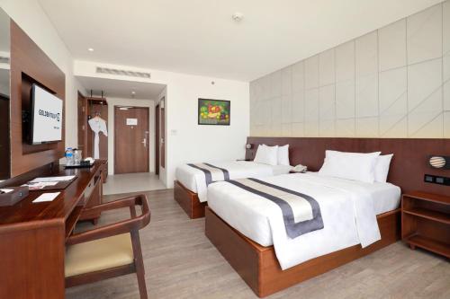 a hotel room with two beds and a desk at Golden Tulip Pontianak in Pontianak
