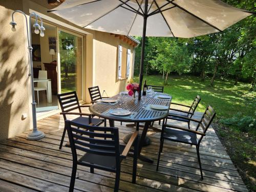 - une table avec des chaises et un parasol sur une terrasse dans l'établissement La villa Le Petit Bois, près Rocamadour, Padirac, à Lavergne
