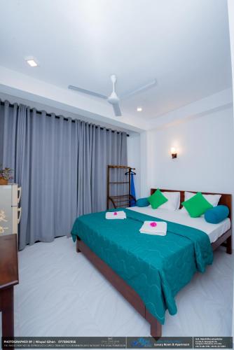 a bedroom with a bed with blue and green sheets at BLUE WHALES HOTEL in Hikkaduwa