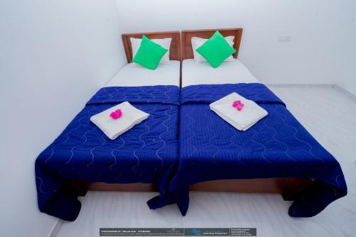 a bed with a blue comforter and four pillows at BLUE WHALES HOTEL in Hikkaduwa