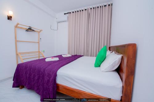 a bedroom with a bed with purple and white pillows at BLUE WHALES HOTEL in Hikkaduwa