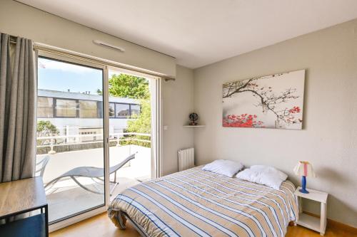 a bedroom with a bed and a sliding glass door at L'Appart du Marché - A quelques min de la plage in Pornichet