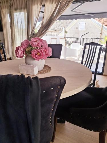 a table with a vase with pink flowers on it at CasaCalla in Okrug Donji