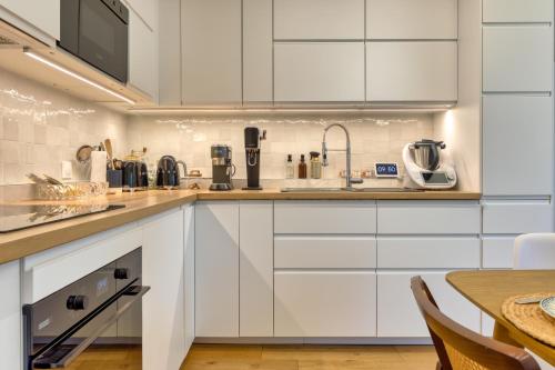 une cuisine avec des armoires blanches et une table dans l'établissement Adorable maison de 75m2 avec grande terrasse et barbecue - 3 chambres, à Touques