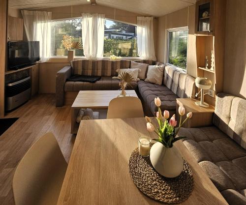 a living room with a couch and a table at Chalet De VeerWater in Recreatiepark De Veerstal in Lathum