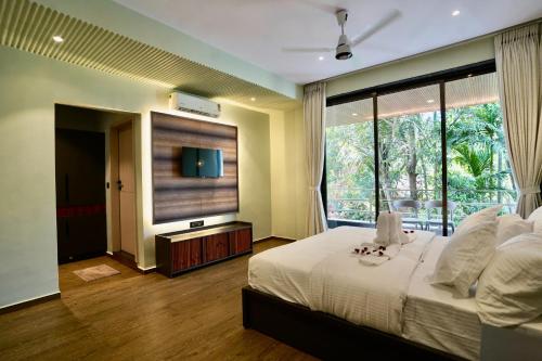 a bedroom with a large bed and a large window at Bhumiputra stays in Pernem