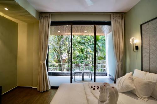 a bedroom with a bed and a large window at Bhumiputra stays in Pernem