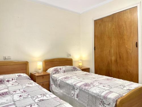 two beds in a bedroom with two lamps on tables at La Solana in Roses