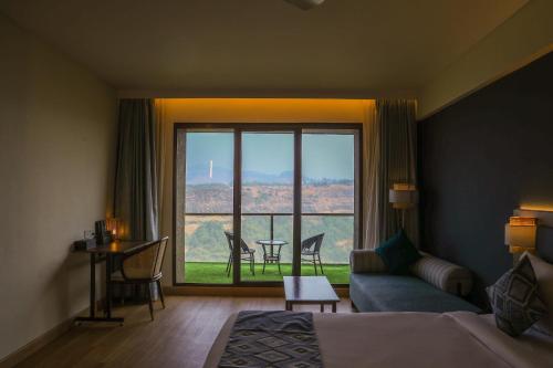 a hotel room with a bed and a large window at Ikshana Resort and Spa, Khandala in Lonavala