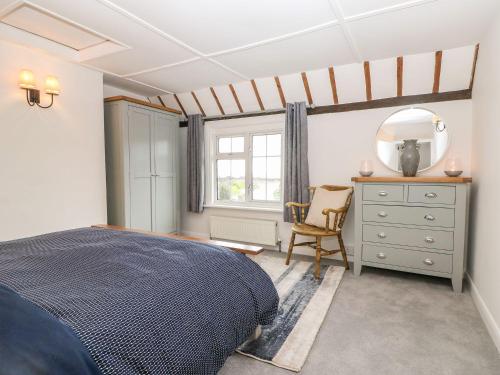 a bedroom with a bed and a dresser and a mirror at 2 Seaview Cottages in Pevensey