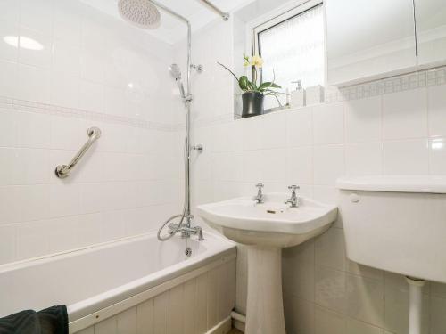 a white bathroom with a sink and a bath tub at 2 Seaview Cottages in Pevensey