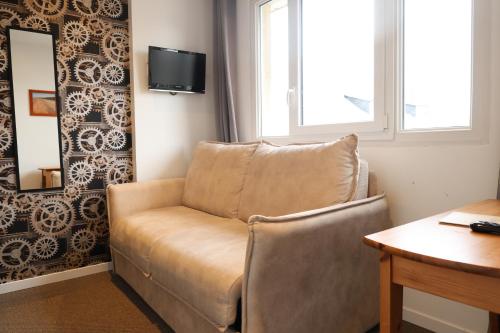 a living room with a couch and a window at Le Clos Normand in Saint-Aubin-sur-Mer