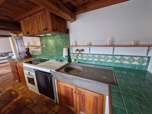 Il dispose d'une cuisine avec un évier et du carrelage vert. dans l'établissement Grande maison de village avec piscine chauffée, à Faucon-de-Barcelonnette