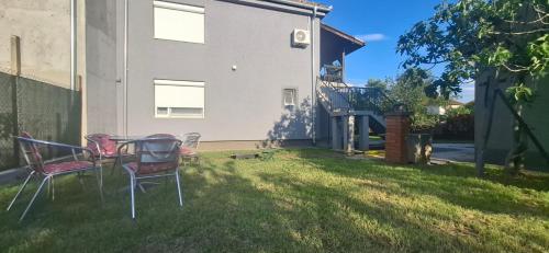 a yard with chairs and a table in the grass at Apartman Marija in Kladovo