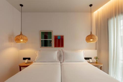 a bedroom with a white bed with two lamps at Elisabeth by the Sea Hotel in Tossa de Mar