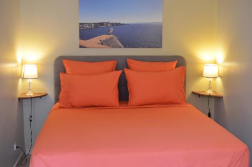 - une chambre avec un lit avec des draps orange et 2 lampes dans l'établissement Rivoli Center Terrasse Clim Parking, à Nice
