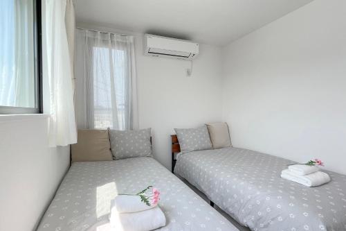 a small bedroom with two beds and a window at 鎌倉 江ノ島 新築貸切一戸建て全館浄水システム完備 海近く 江ノ島が見える 露天テラス 無料駐車2台付 in Kamakura