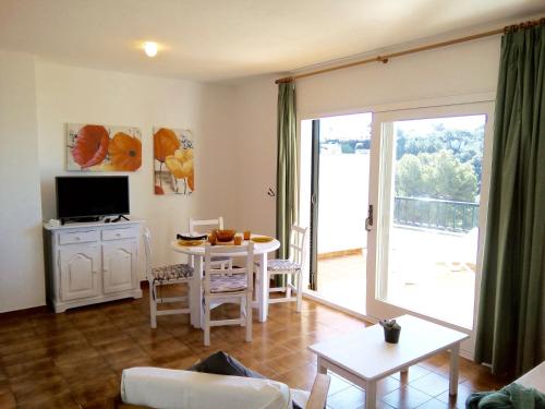 a living room with a table and a tv and a living room at Apartamentos Encanto Del Mar in Cala Galdana