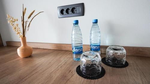 two bottles and two glasses on a wooden table at Hiša na Hribu- A Peaceful Hilltop Escape above river Kolpa in Kostel