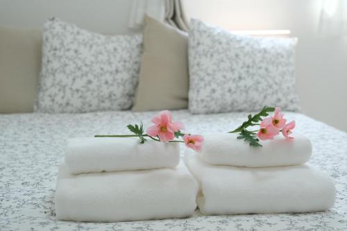 two towels with flowers on top of a bed at 鎌倉 江ノ島 新築貸切一戸建て全館浄水システム完備 海近く 江ノ島が見える 露天テラス 無料駐車2台付 in Kamakura