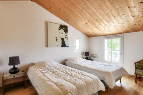 two beds in a bedroom with a wooden ceiling at Piscine chauffee 800 m de la plage villa pour 8 in Le Grand Vieil