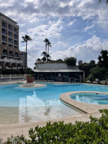 une grande piscine devant un immeuble dans l'établissement Cannes Beach Residence vue mer et pisicne, à Cannes