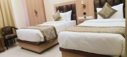 a hotel room with two beds with white sheets at Hotel Mantavya in Kakarmatha