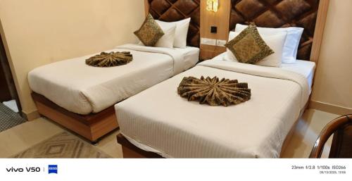 two beds in a hotel room with white sheets at Hotel Mantavya in Kakarmatha