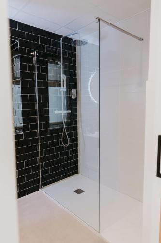 a glass shower in a bathroom with black tiles at Hulot B&B Valencia in Valencia