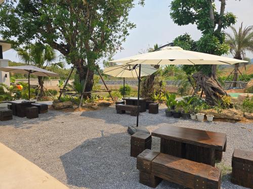 a patio with tables and umbrellas in a park at My Paradise Chiang Rai in Ban Doi Hang