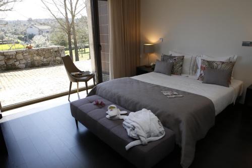 a bedroom with a bed with a chair and a window at Solar Dos Cáceres in Fornos de Algodres