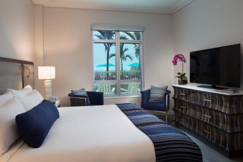 um quarto de hotel com uma cama grande e uma televisão em Treasure Island Beach Resort em St Pete Beach
