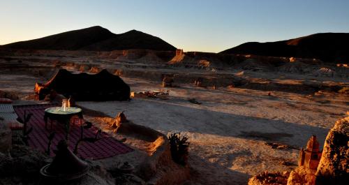 a view of a desert with a table and tents at Campement Akka Nait Sidi - Tissint in Tissint