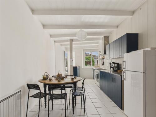 une cuisine avec une table, des chaises et un réfrigérateur dans l'établissement 800 m de la plage - Maison pour 6 au Bois-Plage, au Bois-Plage-en-Ré