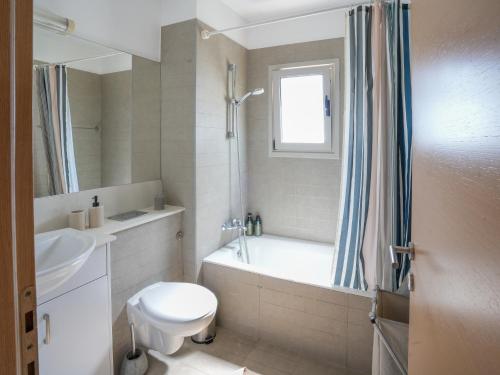 a bathroom with a tub and a toilet and a sink at Mediterranean Escape - Steps from the Beach Apartment with Pool in Limassol